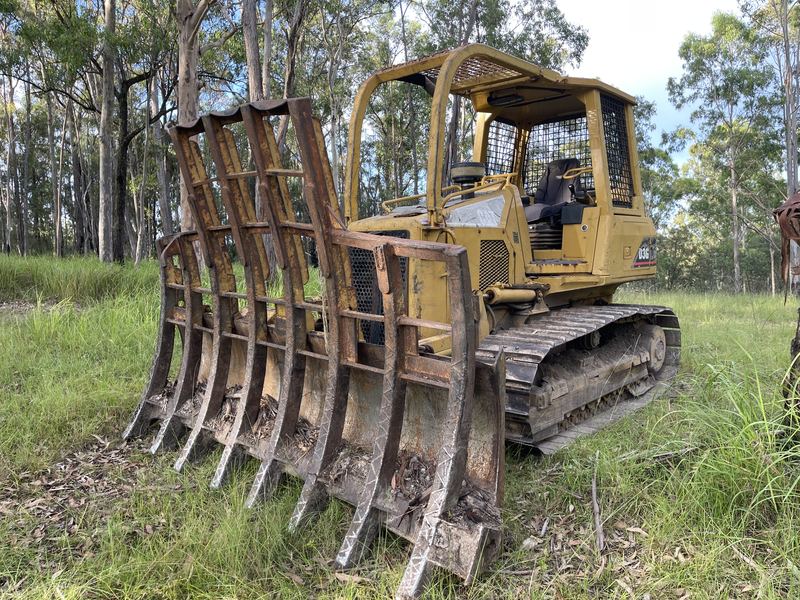 Caterpillar D3G dozer fitted with a stick rake for land clearing