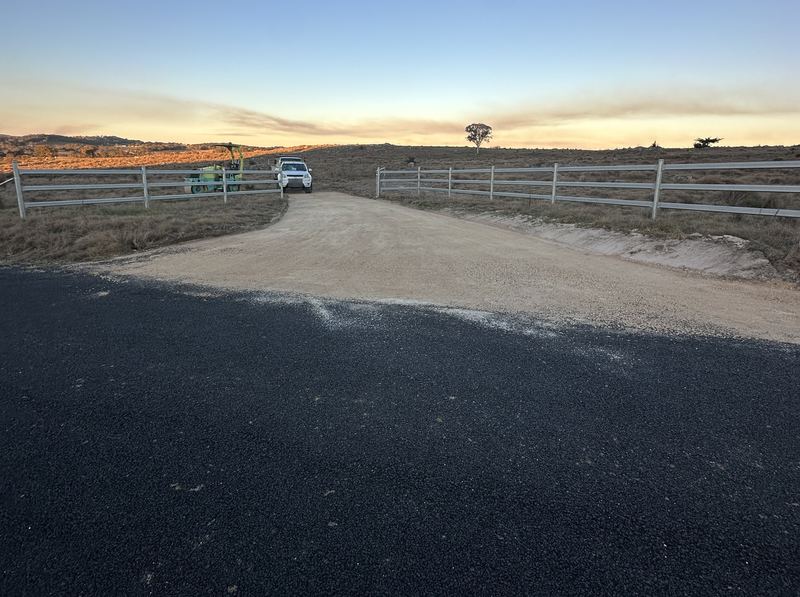 Step 3: Finished gravel base on a rural driveway entrance at sunset, ready for sealing