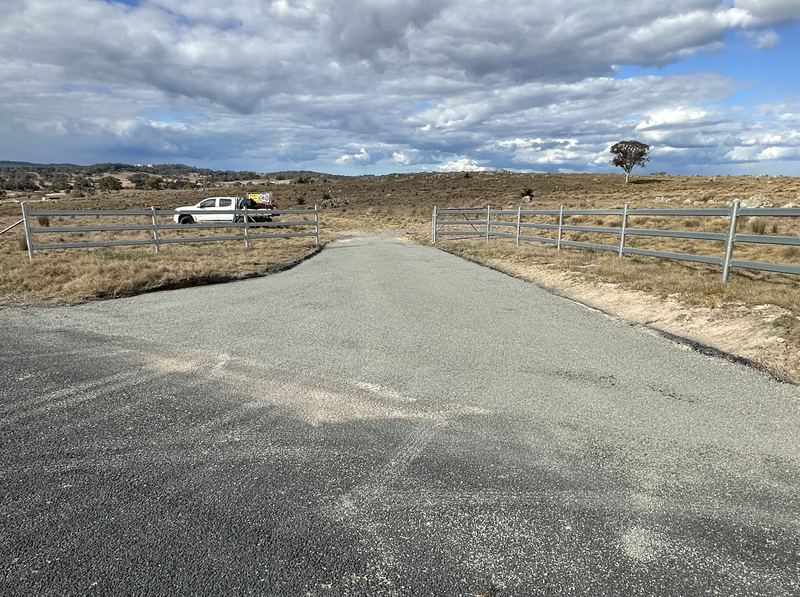 Finished bitumen seal on a rural driveway entrance