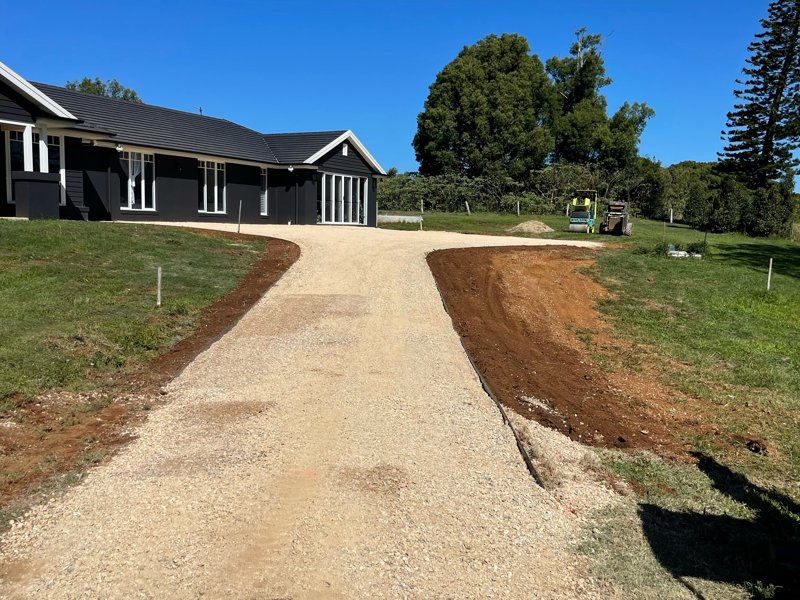 Freshly formed gravel driveway leading up to a new home, with shaped edges